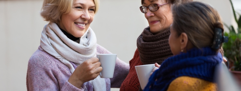 Group of smiling mature women drinking tea at balcony