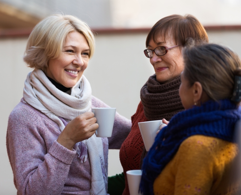 Group of smiling mature women drinking tea at balcony