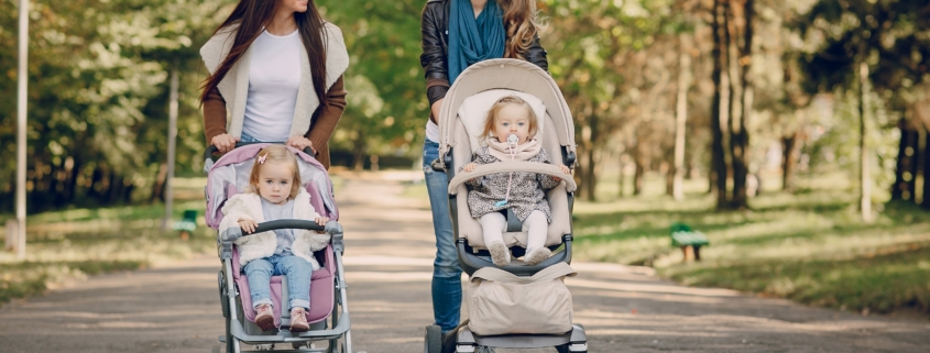 young mother walking with her baby and carries it in a beautiful pram