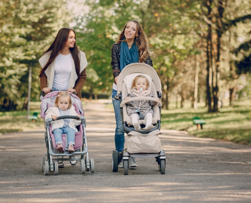 young mother walking with her baby and carries it in a beautiful pram