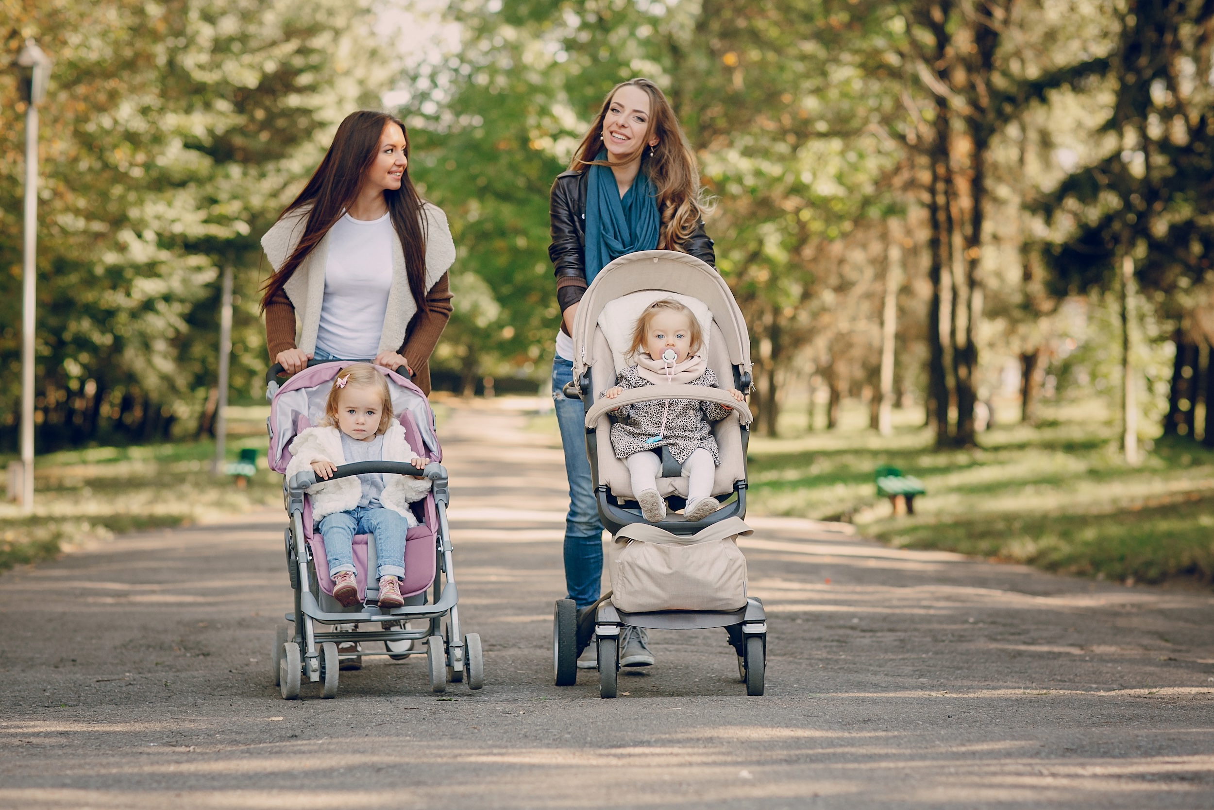 young mother walking with her baby and carries it in a beautiful pram